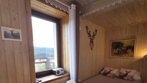 Puuinen mökkihuone, jossa on sänky, pöytä ja ikkuna.