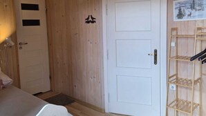 Puinen huone, jossa on valkoinen ovi, pieni hylly ja pöytä.