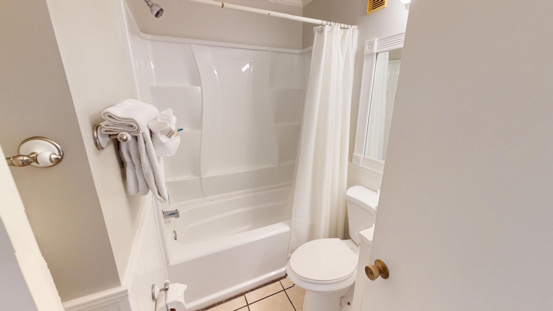 A bathroom with a shower, toilet, and towel rack.