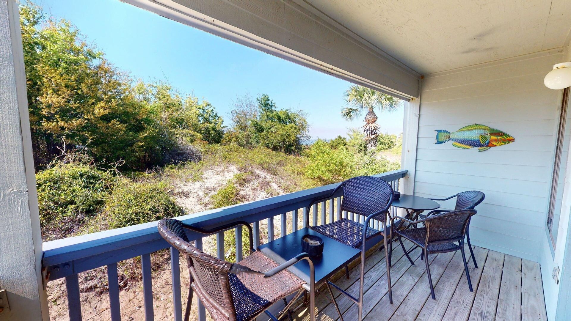 A covered outdoor area with a table and chairs, a decorative fish mural, and a view of the surrounding landscape.