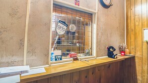 A reception desk with a window, a clock, and a teddy bear. - Heart of Dixie Motel Near Auburn AL (Dadeville)