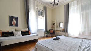 A bedroom with a large bed, a smaller sofa bed, a desk, and a chair.