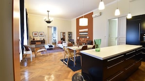 A modern kitchen with a central island, pendant lighting, and a dining area with a table and chairs.