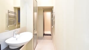 A modern bathroom with a white sink, chrome fixtures, and a glass shower enclosure.