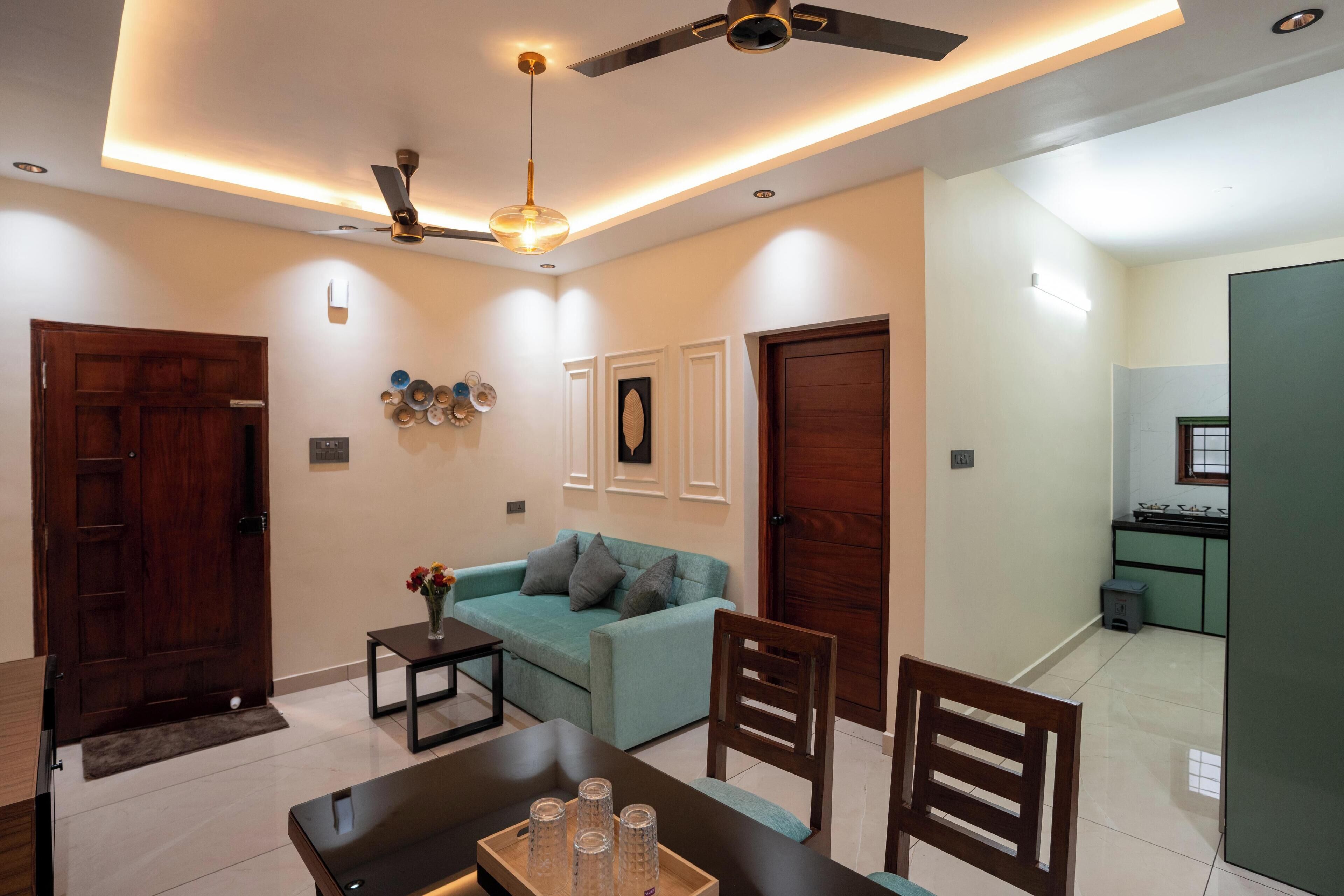 A modern living room with a sofa, dining table, chairs, and a ceiling fan.
