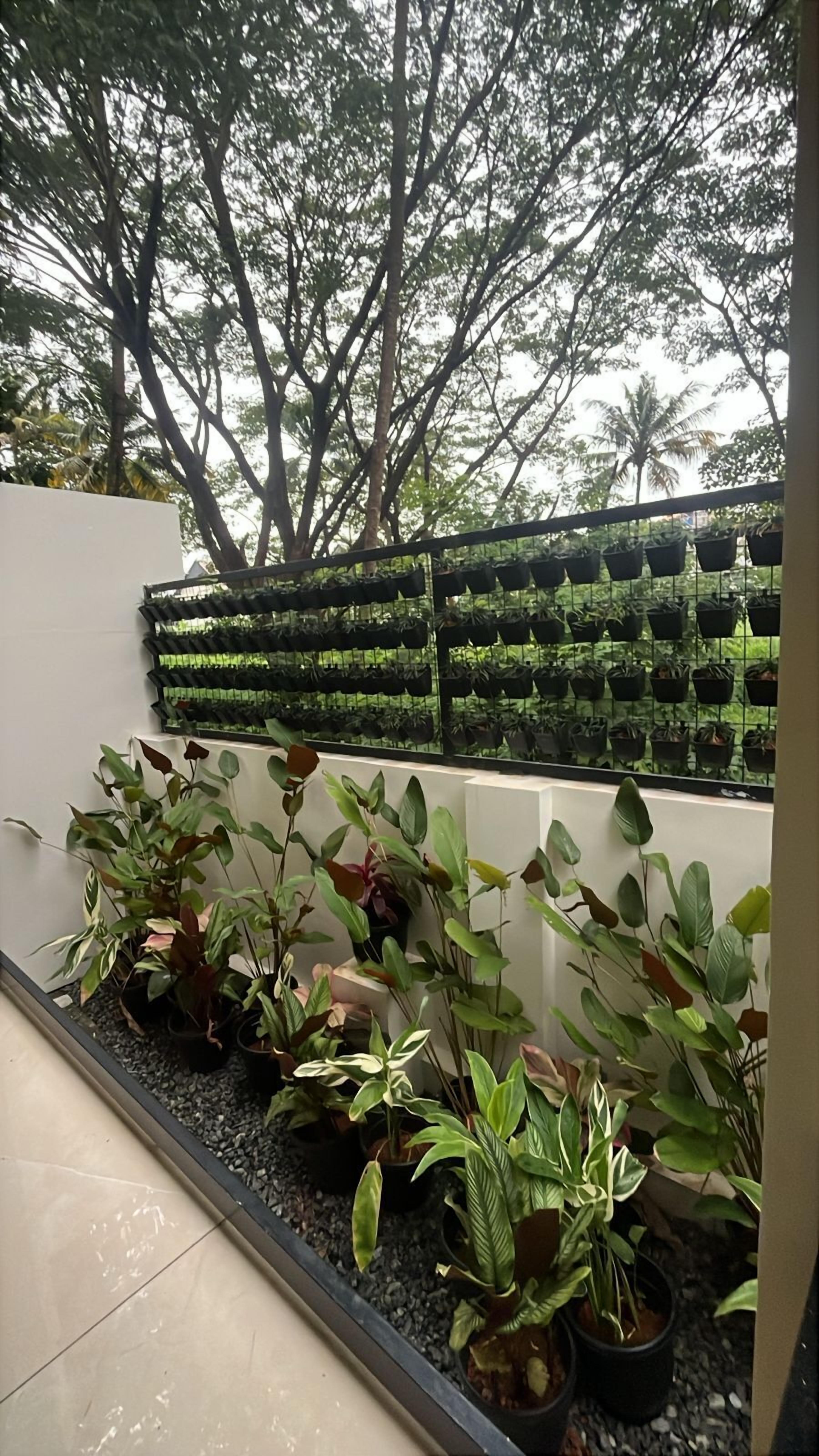 A balcony with potted plants and a view of trees.