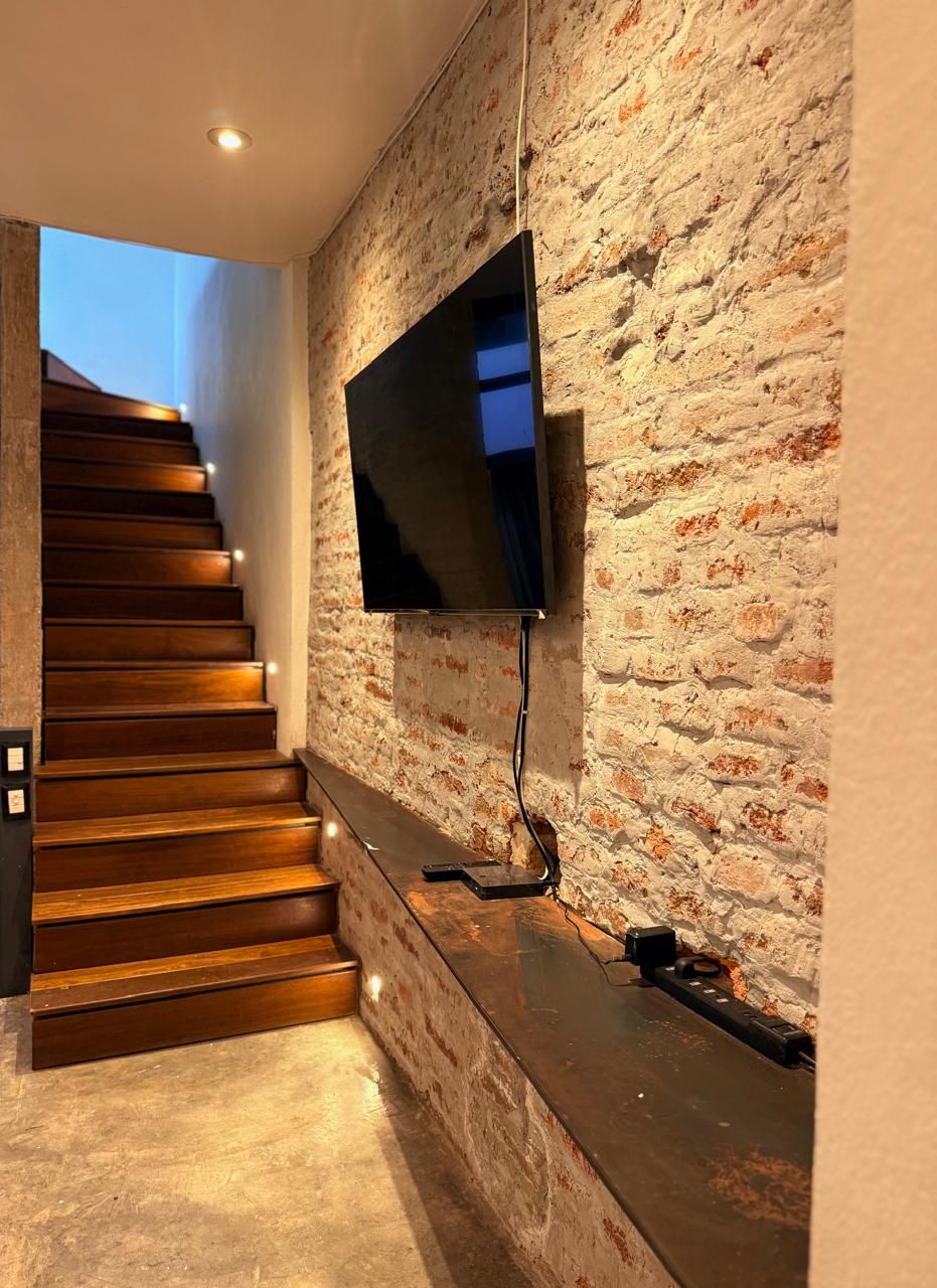 A modern staircase with wooden steps and a flat wall-mounted TV.