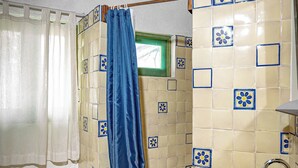 Een badkamer met toilet, wastafel en een douchecabine met een blauw gordijn.