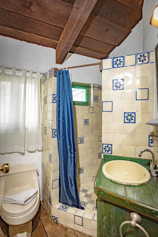 A bathroom with a toilet, a sink, and a shower area with a blue curtain.