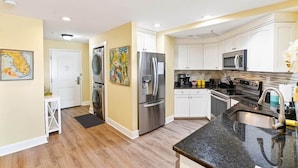 A modern kitchen with stainless steel appliances, white cabinetry, and a granite countertop.
