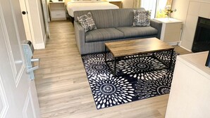 Habitación de hotel pequeña con cama, sofá y una mesita.