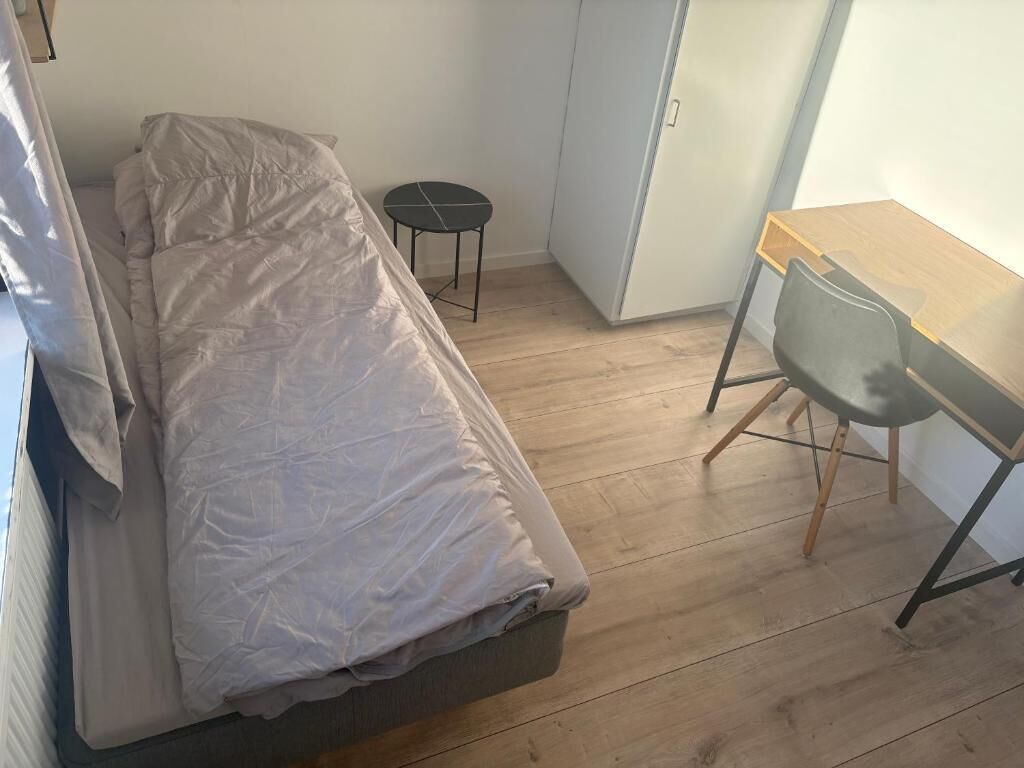 A small room with a bed, a desk, and a chair.