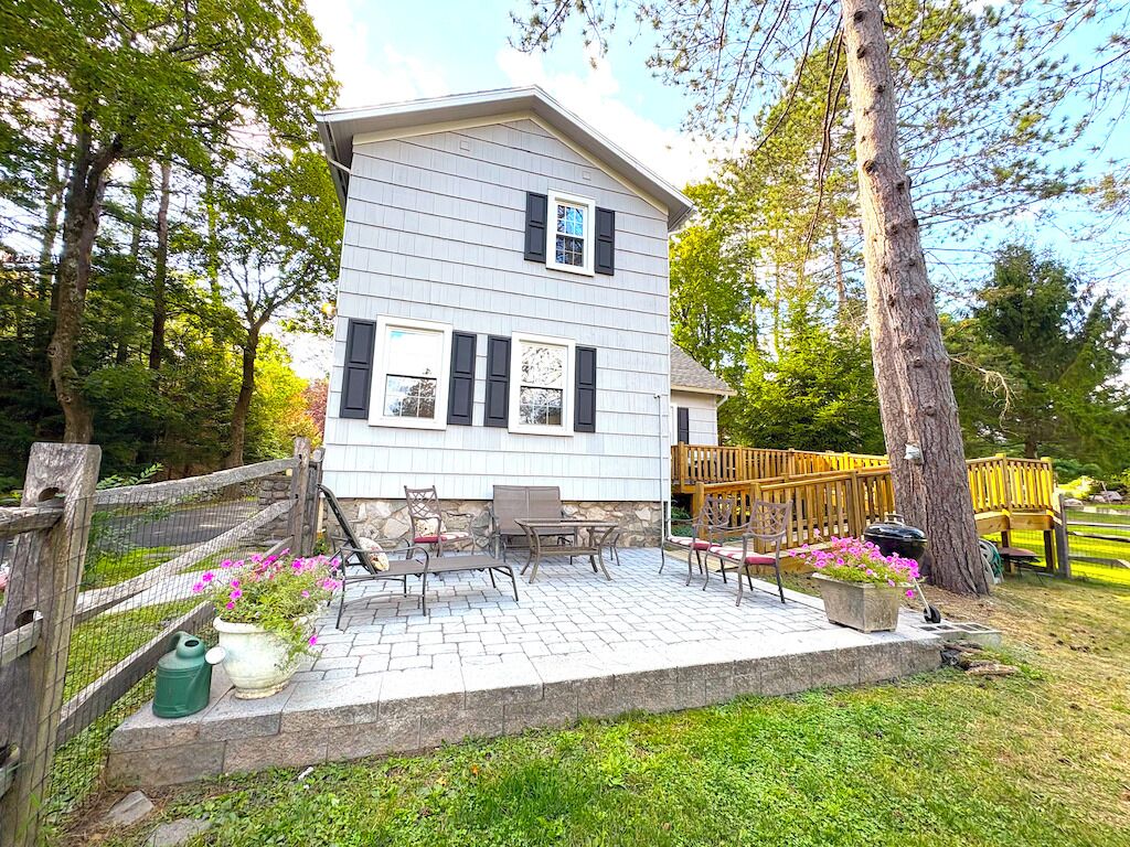 A two-story house with a patio area featuring outdoor furniture and potted plants.