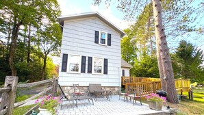 A two-story house with a patio area featuring outdoor furniture and potted plants. - Summer Pocono Cabin Near Skytop Lodge with Fenced Yard; Wkly/Mthly Discounts (Canadensis)