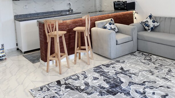A modern kitchen with white cabinets, a marble backsplash, and a central island with stools. - star- guest house (Luxor Governorate)