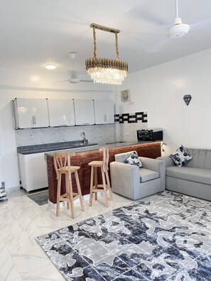 A modern kitchen with white cabinets, a marble backsplash, and a central island with stools. - star- guest house (Luxor Governorate)