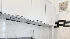 A modern kitchen with white cabinets, a granite countertop, a stainless steel sink, and a gas stove. - star- guest house (Luxor Governorate)