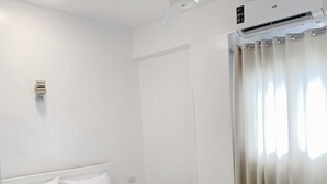 A bedroom with a bed, a ceiling fan, an air conditioning unit, and a window with curtains. - star- guest house (Luxor Governorate)