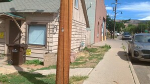 A residential street with houses, a trash bin, and parked cars. - Old Hunting Cabin Apartment on High St (Collbran)