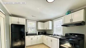 A modern kitchen with white cabinets, a black refrigerator, a stove, and a microwave.