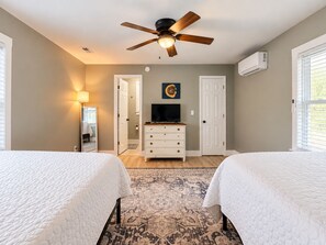 A bedroom with two beds, a ceiling fan, a television, a dresser, and a patterned rug. - Waterfront Beaufort Home - Marsh Views & Screened Porch! (Beaufort)