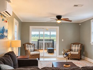 A living room with a sofa, two chairs, a table, and a ceiling fan. - Waterfront Beaufort Home - Marsh Views & Screened Porch! (Beaufort)