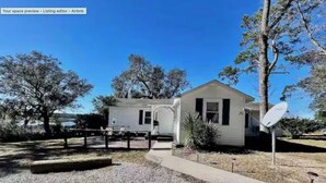 A single-story house with a front porch, a satellite dish, and a gravel driveway.