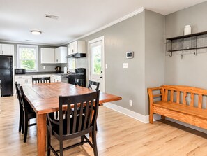 A modern kitchen with white cabinets, a wooden dining table, and a bench. - Waterfront Beaufort Home - Marsh Views & Screened Porch! (Beaufort)