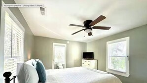 A bedroom with a bed, a ceiling fan, a dresser, and a television.