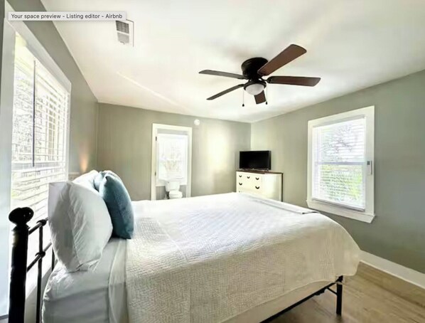 Un dormitorio con cama, ventilador de techo, cómoda y televisor.