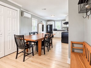 A modern kitchen with white cabinets, a wooden dining table, and black chairs.