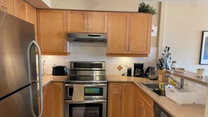 A modern kitchen with stainless steel appliances, wooden cabinets, and a tiled backsplash.