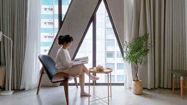 A modern room with a large window, a chair, a small table, and a potted plant. - Express by M Village Nguyen Van Thu, a brand of Modern Village Lifestyle (Ho Chi Minh City)
