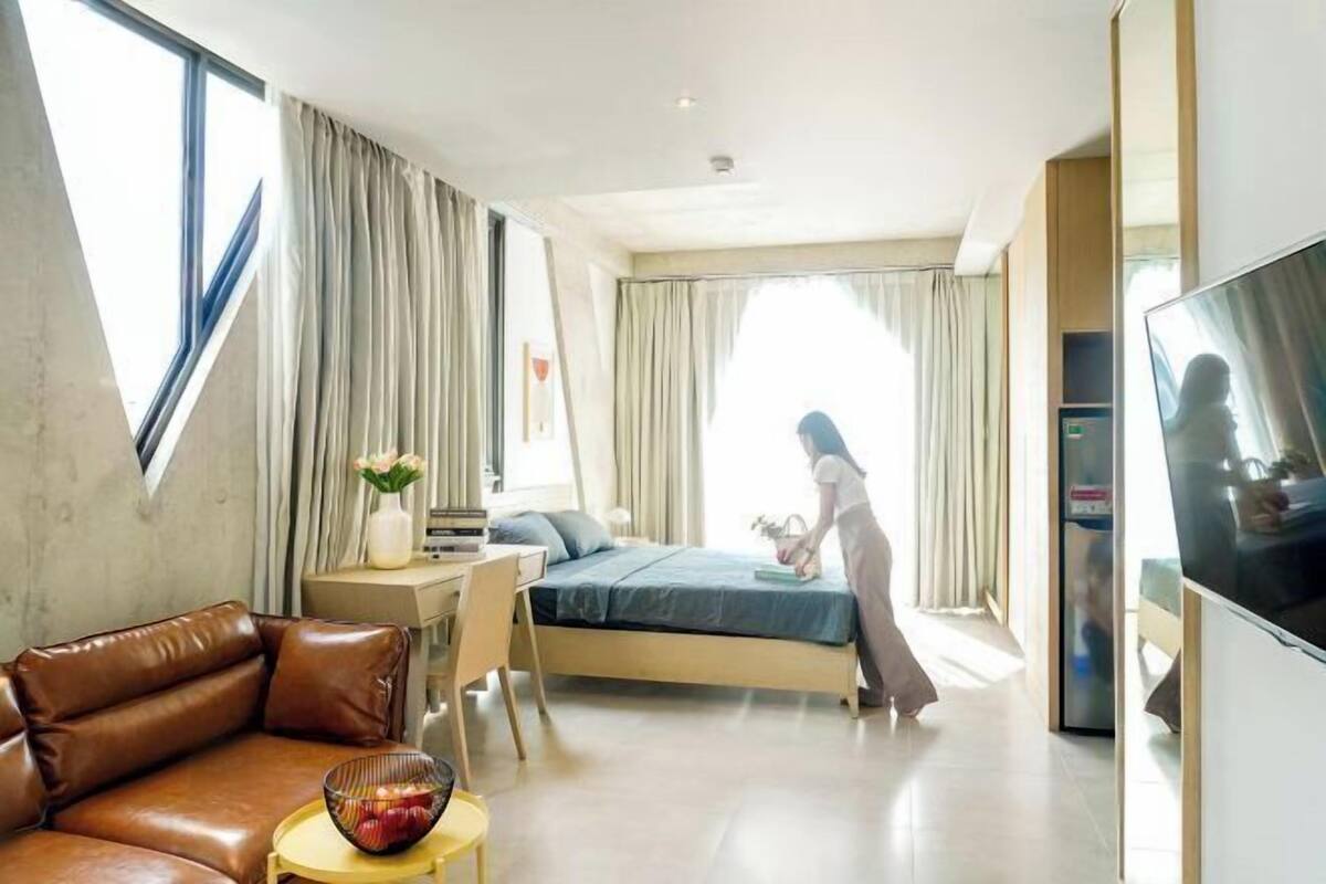Ein modernes Hotelzimmer mit Bett, einer Couch, einem Fernseher und einem Schreibtisch mit Stuhl.