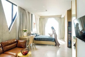 Ett modernt hotellrum med en säng, en soffa, en TV och ett skrivbord med en stol.
