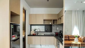 A modern kitchen with wooden cabinets, a black countertop, and a built-in oven. - Express by M Village Nguyen Van Thu, a brand of Modern Village Lifestyle (Ho Chi Minh City)