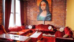 A room with a red velvet sofa set, a painting of the Mona Lisa on the wall, and a brick wall. - Broadway Penthouse: Stadium View (Nashville)