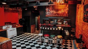A bar area with a checkered floor, stools, a bar counter, and a neon sign. - Broadway Penthouse: Stadium View (Nashville)