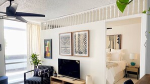 Uma sala de estar moderna com um sofá, TV e obras de arte na parede.