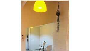A room with a bed, a table with chairs, a hanging plant, and a door leading to another room. - Cacao House (Capesterre-Belle-Eau)