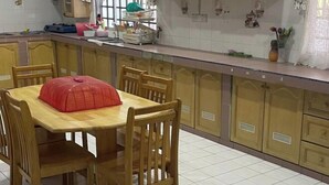 Una cuina amb armaris de fusta, un sòl de rajola i una taula de dinar amb cadires.