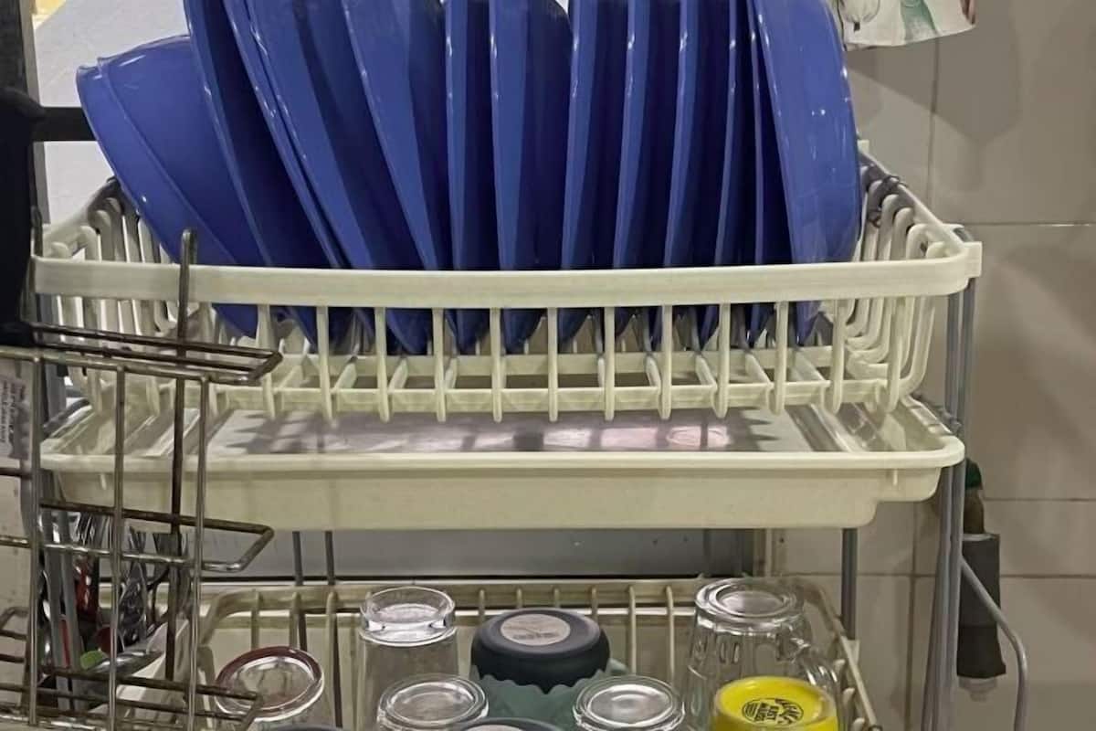 A dish rack with blue plates and a tray with glass jars and lids.