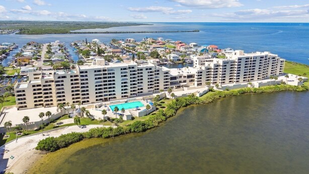 A coastal hotel with multiple buildings, a swimming pool, and a marina. - Cozy 2-bedroom condo with heated pool, fitness room, game room, Gulf Front (Hudson)