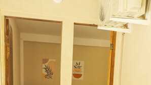A room with a bed, a wooden table with a vase, and a mirror on the wall. - Pousada Raízes da Mata (Santa Cruz Cabrália)