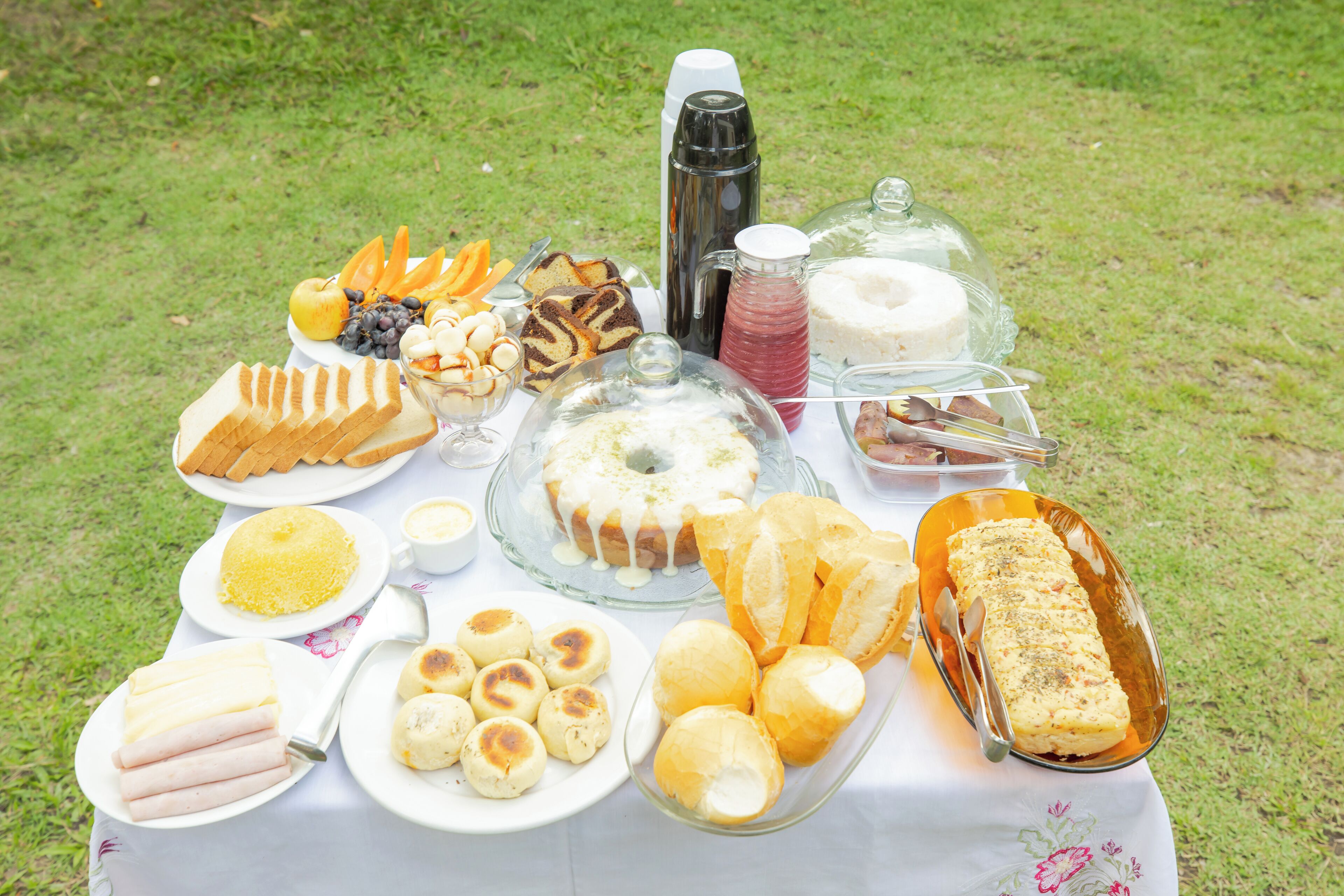 A table with various food items including bread, pastries, and a covered dessert.