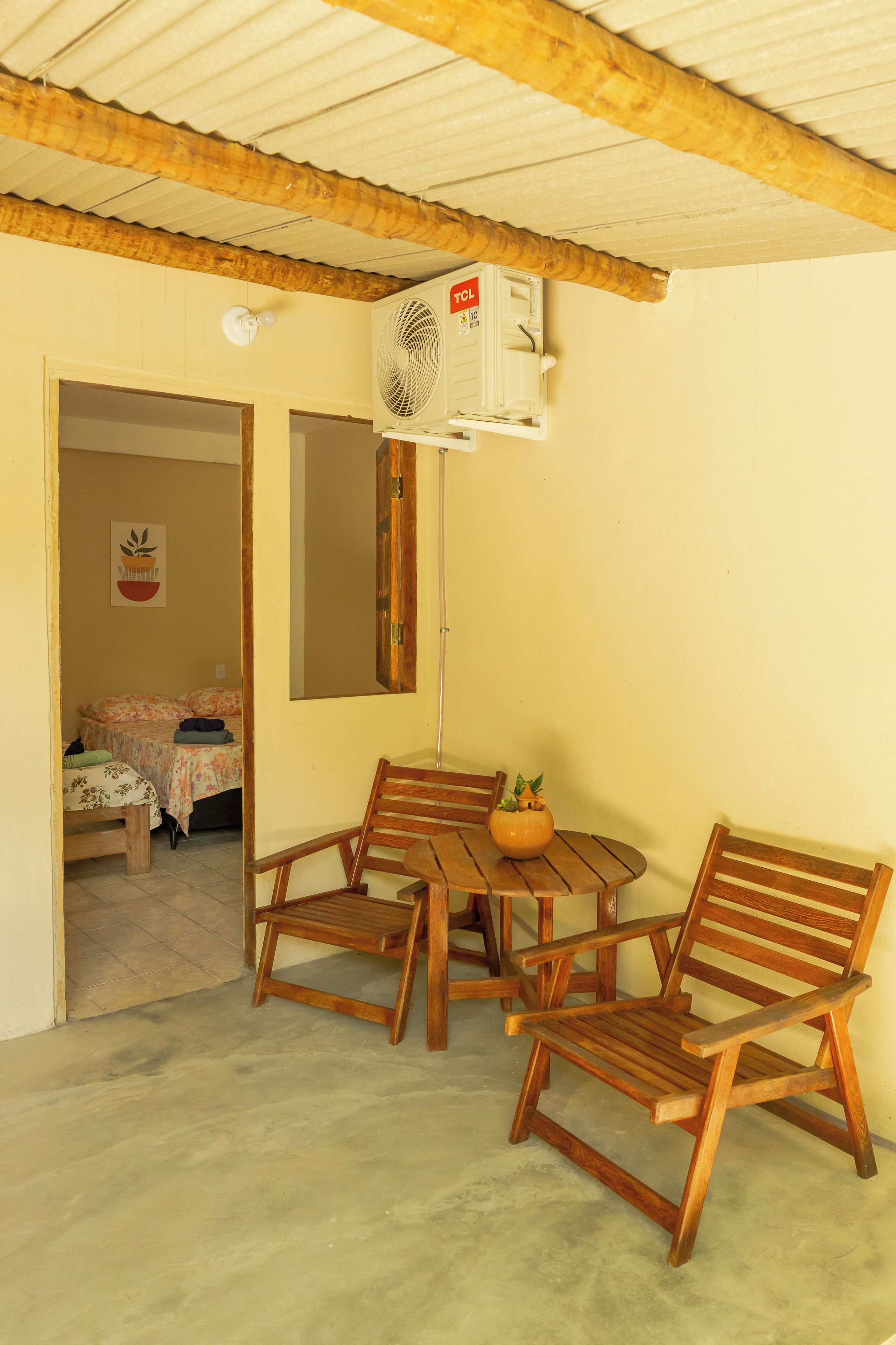 Une pièce avec une table et des chaises en bois, un ventilateur de plafond et un lit à l’arrière-plan.
