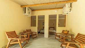 A room with wooden furniture, including chairs and a table, and a bed with a floral bedspread. - Pousada Raízes da Mata (Santa Cruz Cabrália)