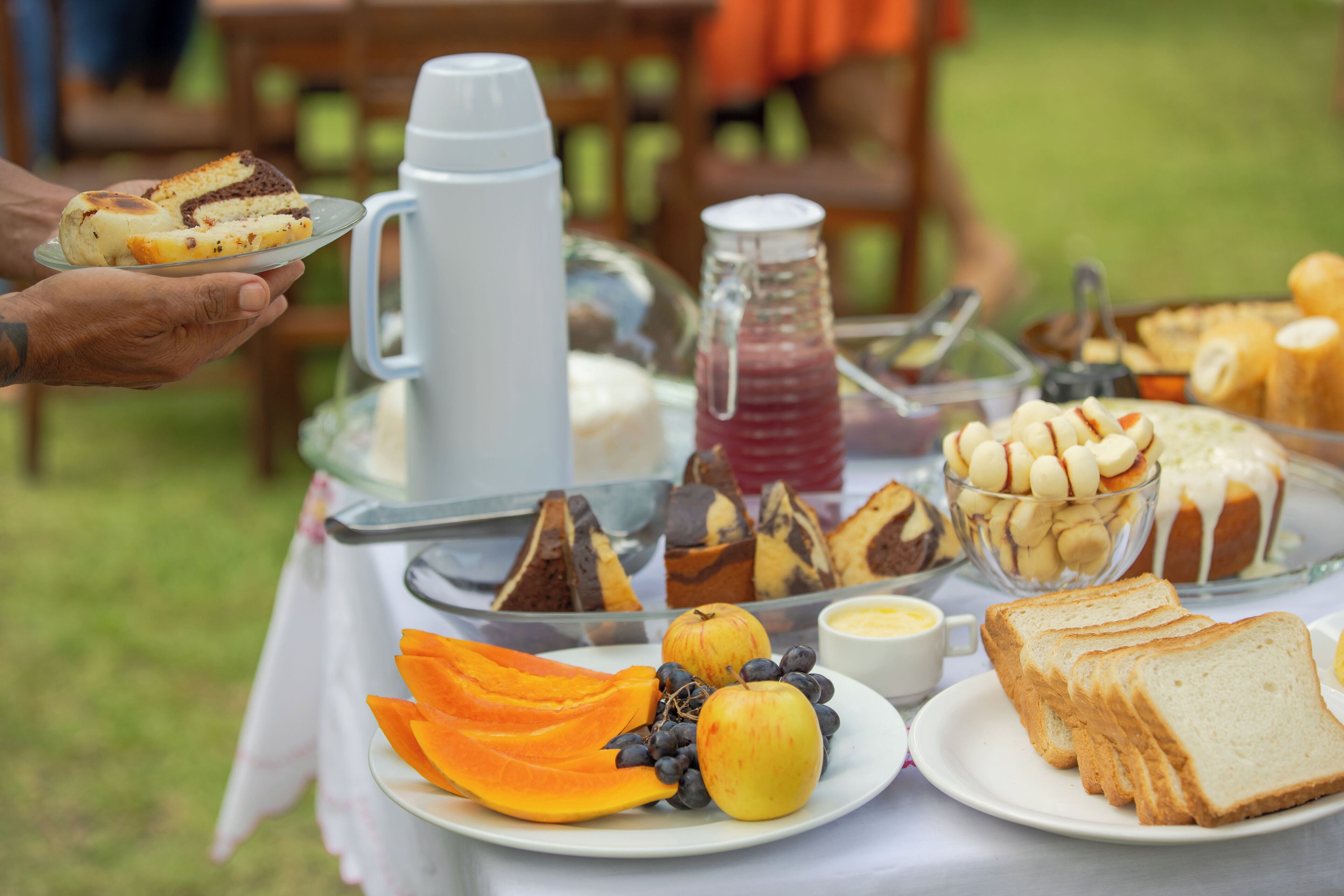 Una mesa de buffet con diversos alimentos, como pan, pasteles y frutas.