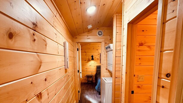 Ein Innenraum-Flur mit Holzboden, einem Deckenventilator, einem kleinen Tisch und einem Kühlschrank.