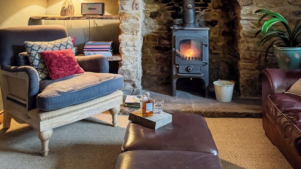 A cozy living room with a stone fireplace, a sofa, a coffee table, and a hanging light fixture.